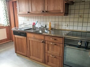 Una cocina con armarios de madera, lavavajillas, fregadero y estufa.