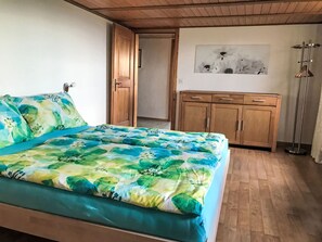 Un dormitorio con una cama, un armario de madera y un cuadro en la pared.