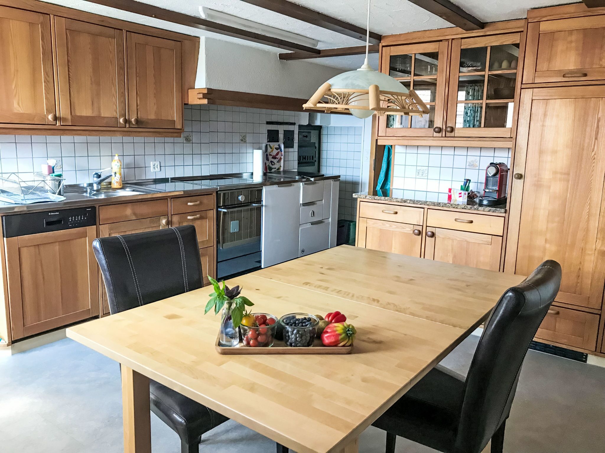 Una cocina con armarios de madera, un lavamanos de acero inoxidable y una mesa de comedor de madera con sillas.