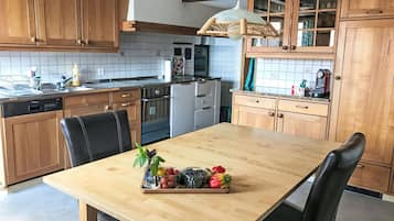 Una cocina con armarios de madera, un lavamanos de acero inoxidable y una mesa de comedor de madera con sillas.