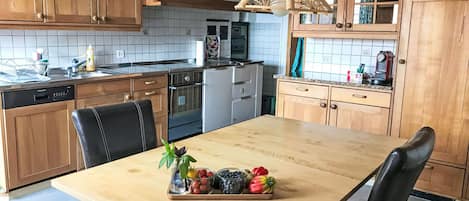 Una cocina con armarios de madera, un lavamanos de acero inoxidable y una mesa de comedor de madera con sillas.