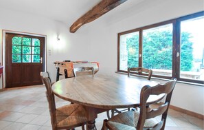 A dining area with a round wooden table, four chairs, a foosball table, and a door with a glass panel. - 2 bedroom stunning home in Saint-André d'Hébertot (Saint-André d'Hébertot)