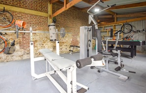 Ein Fitnessstudio mit Hantelbank, Krafttrainingsgeräten und einem Fahrradständer an der Wand.