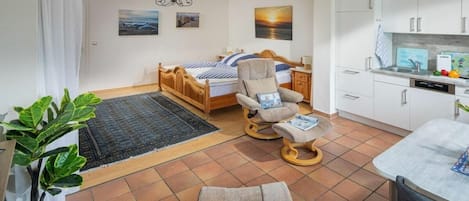 Una camera da letto con un letto, una sedia, una scrivania, un angolo ristoro e una cucina.