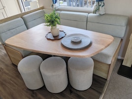 Un comedor con mesa de madera, asientos acolchados y una planta en maceta.