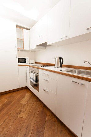 A modern kitchen with white cabinets, a wooden countertop, a built-in oven, and a stainless steel sink. - Spacious Kozna Loft D 2-Bedrooms apartment in Prague Old Town (Prague)