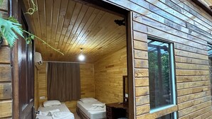 A wooden cabin interior with a bed, a desk, and a window. - Natural Pansiyon (KUMLUCA)