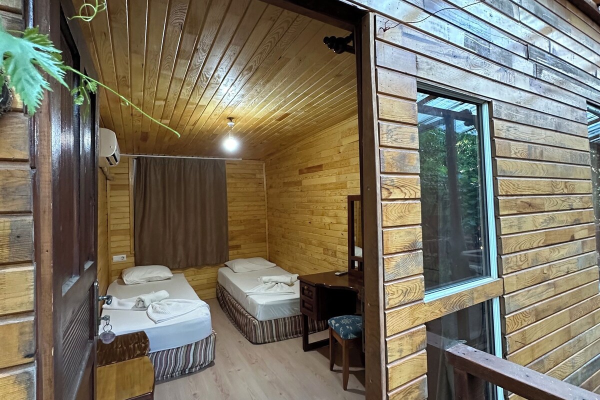 Interior d'una cabana de fusta amb un llit, un escriptori i una finestra.