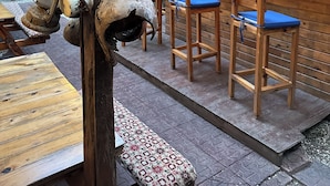 Een rustieke openluchtbars met houten meubels en een bord met de tekst 'NATURAL BAR'.
