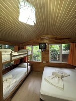 A cabin interior with bunk beds, a television, and windows with curtains.