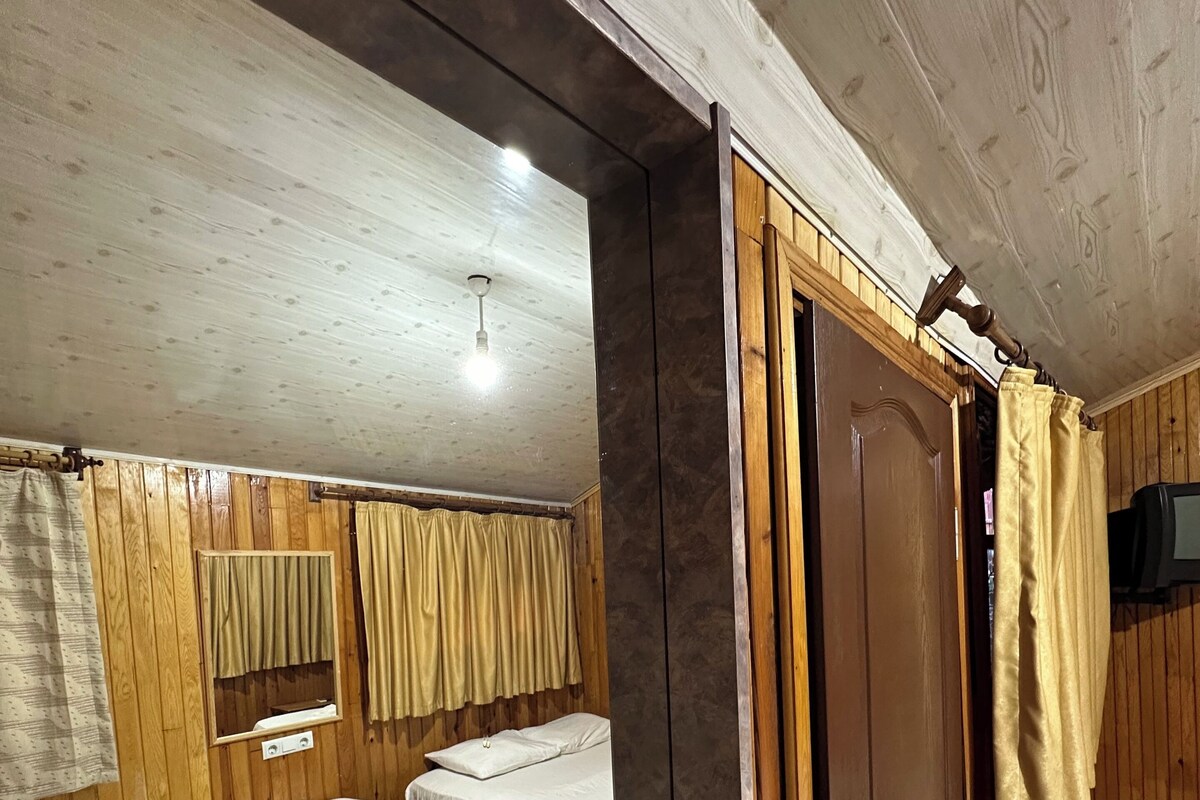 Una habitació amb parets de fusta, un llit, un armari ia una televisió.