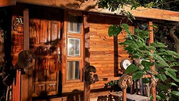 Una cabaña rústica de madera con puerta y ventana, y un porche.