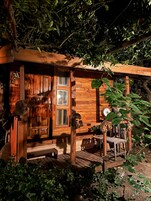 Una cabaña rústica de madera con puerta y ventana, y un porche.