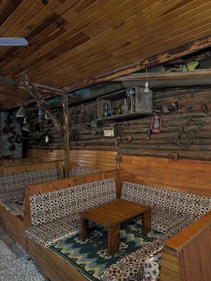 A rustic cabin interior with wooden walls, a patterned rug, and a wooden table.