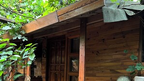 A rustic wooden cabin with a porch, a blue motorcycle, and various tools and equipment.