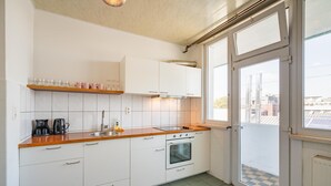 Une cuisine moderne avec des armoires blanches, un plan de travail en bois, un four encastré et une grande fenêtre.