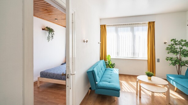 Una habitación con una cama, un sofá, una mesita y una ventana con cortinas.