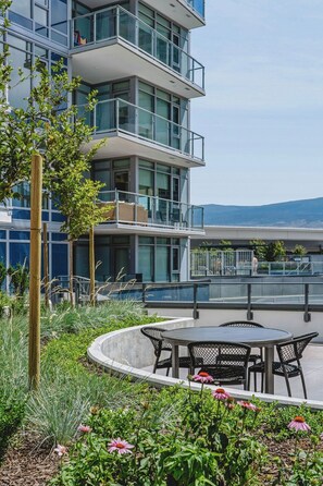 A modern building with multiple balconies, outdoor seating, and a landscaped garden area. - The Southwest Pottery Suite | DT Kelowna 1BR | Pool&Sauna (Kelowna)