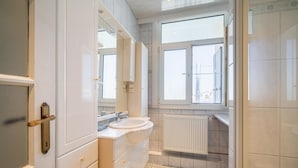 Un baño con lavamanos, espejo y ventana.