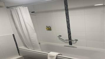 A white tiled shower enclosure with a glass door, a showerhead, and a handheld shower attachment.