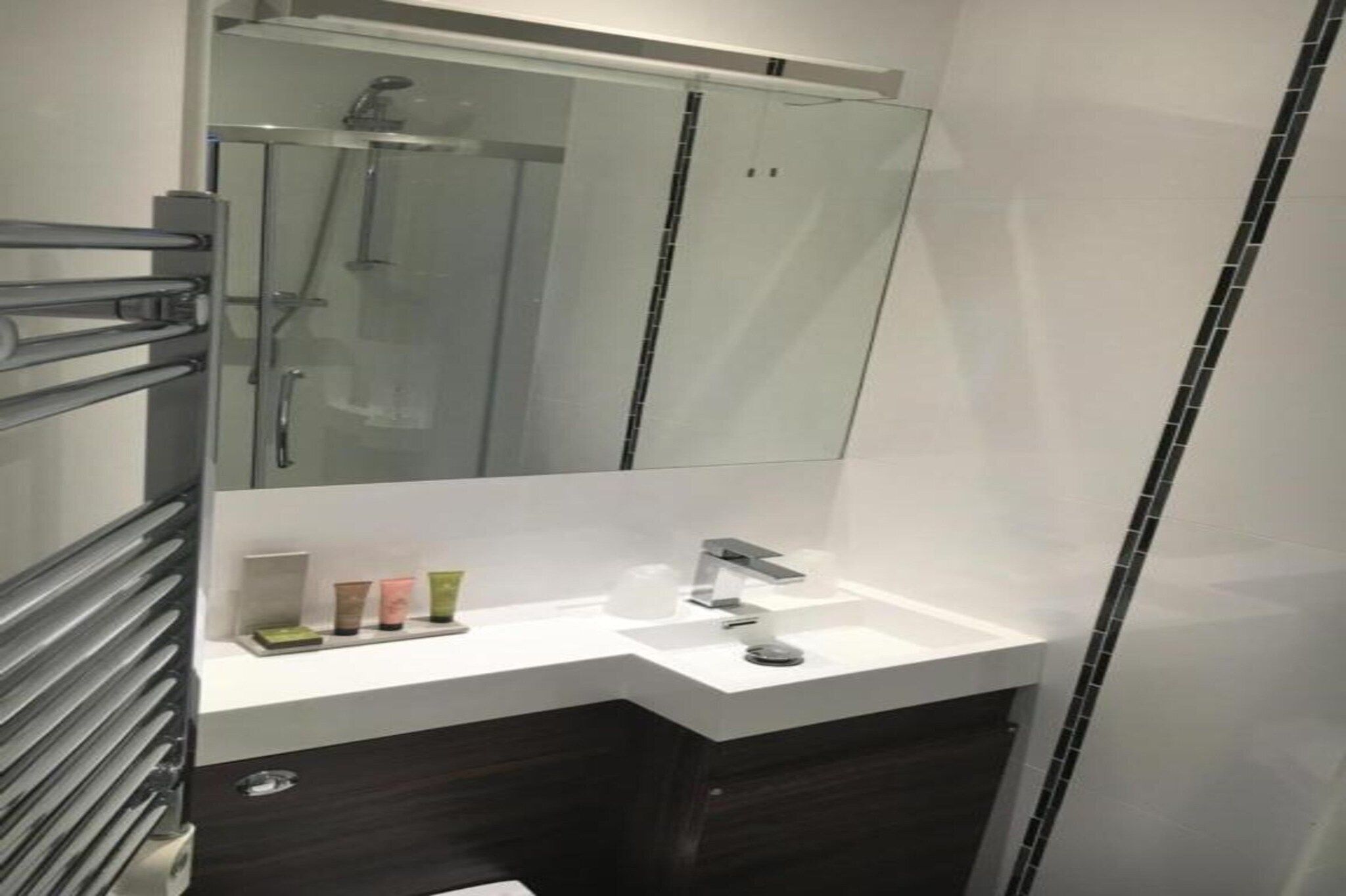 Une salle de bain moderne avec une douche à parois de verre, un lavabo blanc et un miroir au-dessus.