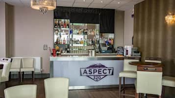 A bar area with a counter, bar stools, and a chandelier.