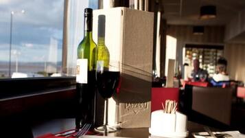 A restaurant setting with a table set for two, a wine bottle, and a menu box.