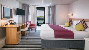 Hotellihuone, jossa on sänky, työpöytä, tuoli, televisio ja näkymä ulos.
