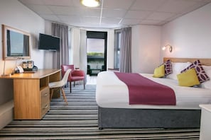 Een hotelkamer met een bed, een bureau, een stoel, een televisie en uitzicht op de omgeving.