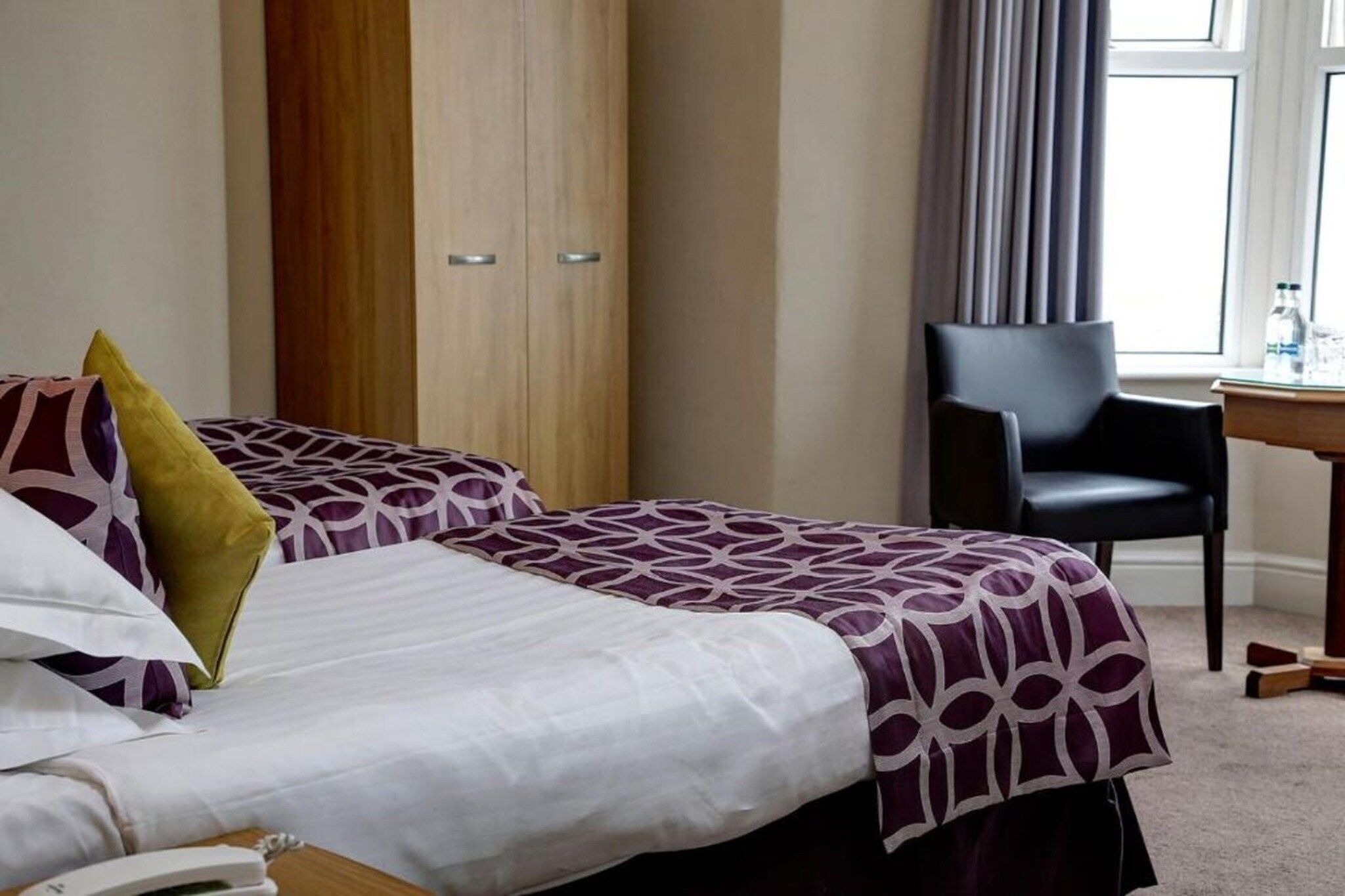 A hotel room with two beds, a desk, and a chair.