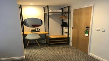 A compact room with a bunk bed, a desk, a chair, a mirror, and a door.