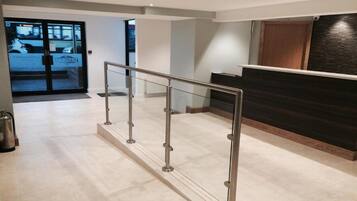 A reception area with a glass partition, a reception desk, and a metal barrier.