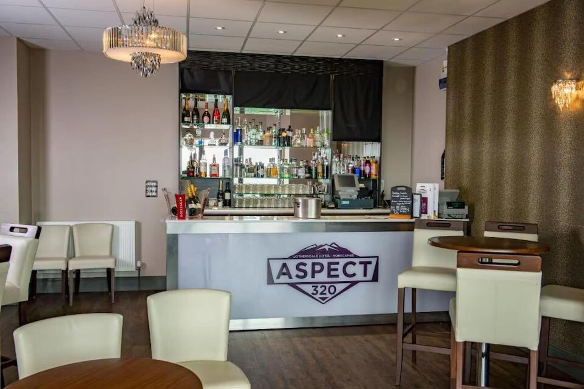 A bar area with a counter, bar stools, and a chandelier.