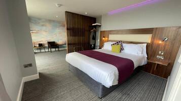A hotel room with a large bed, a wooden headboard, a desk, and a chair.