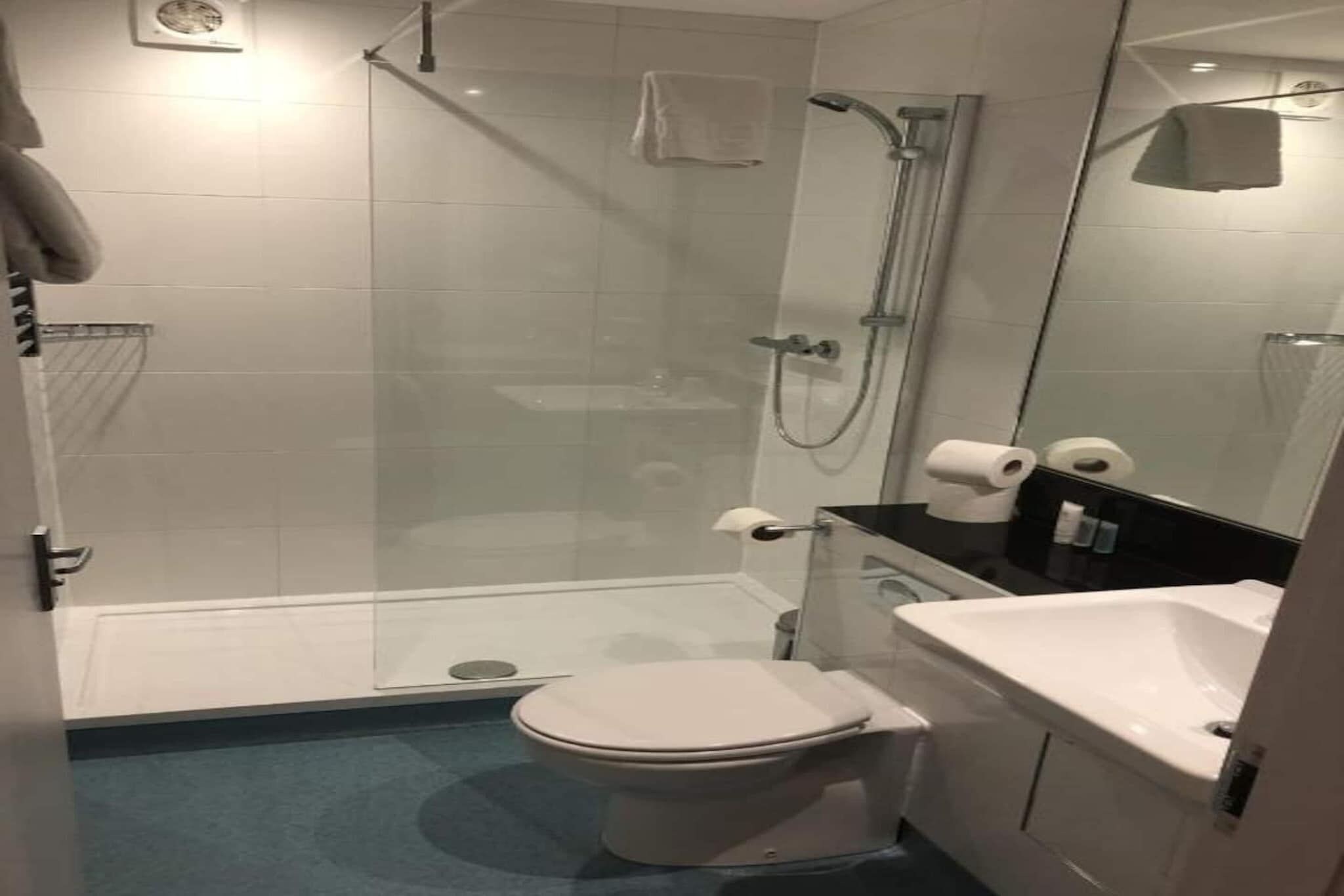 Une salle de bain avec une douche à parois de verre, des toilettes et un lavabo.