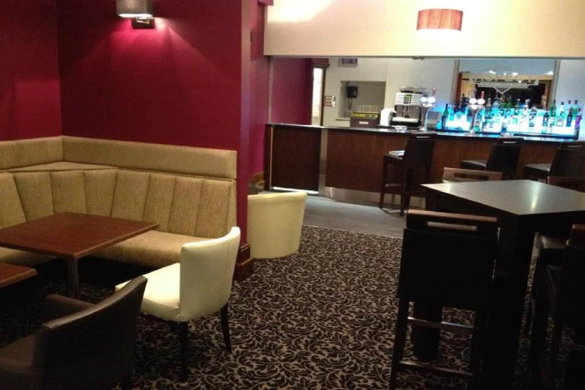 A restaurant interior with a booth seating area, a bar counter, and a patterned carpet.