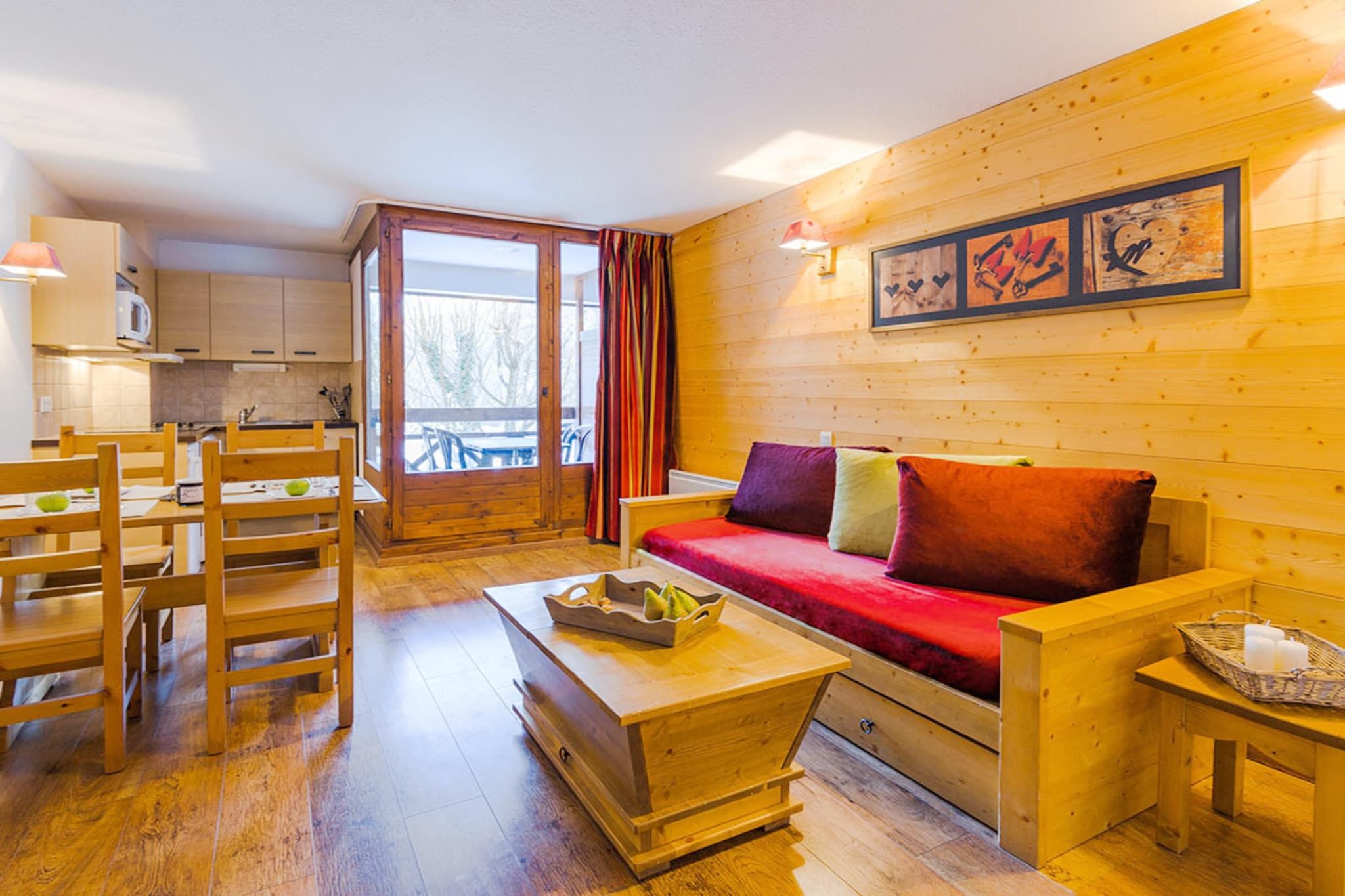 Ein gemütliches Holzinterieur mit einer Couch, einem Esstisch, Stühlen und einer Küchenzeile.