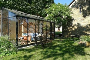A conservatory with a glass roof, a bench, and a table with cushions. - Holiday home with 1 bedroom (Nebelschütz OT Dürrwicknitz)