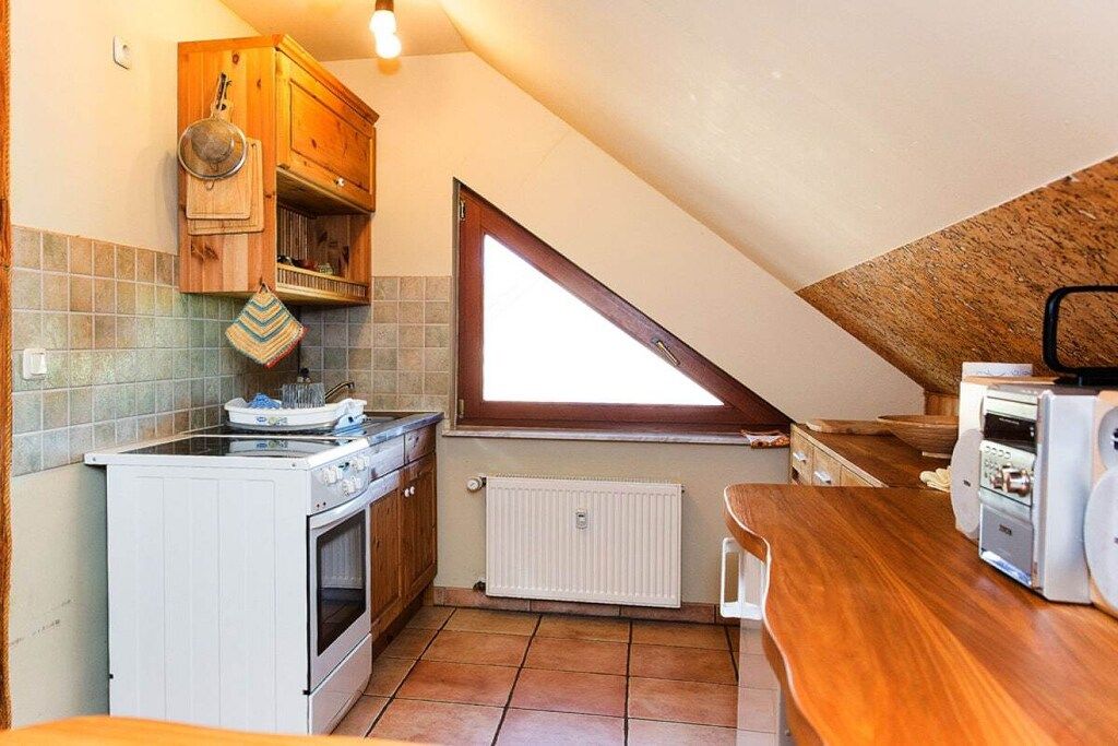 Une cuisine de taille réduite, équipée d’une cuisinière, d’un four et d’une fenêtre.