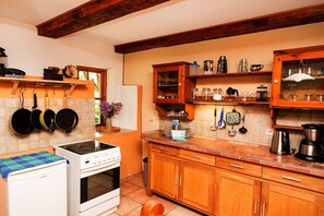 A kitchen with a stove, oven, and various kitchen utensils on shelves. - Grethe Ground Floor || Rockow (Rockow)