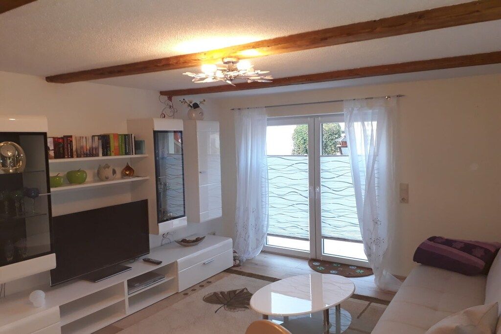A living room with a flat-screen TV, a white sofa, a coffee table, and a bookshelf.