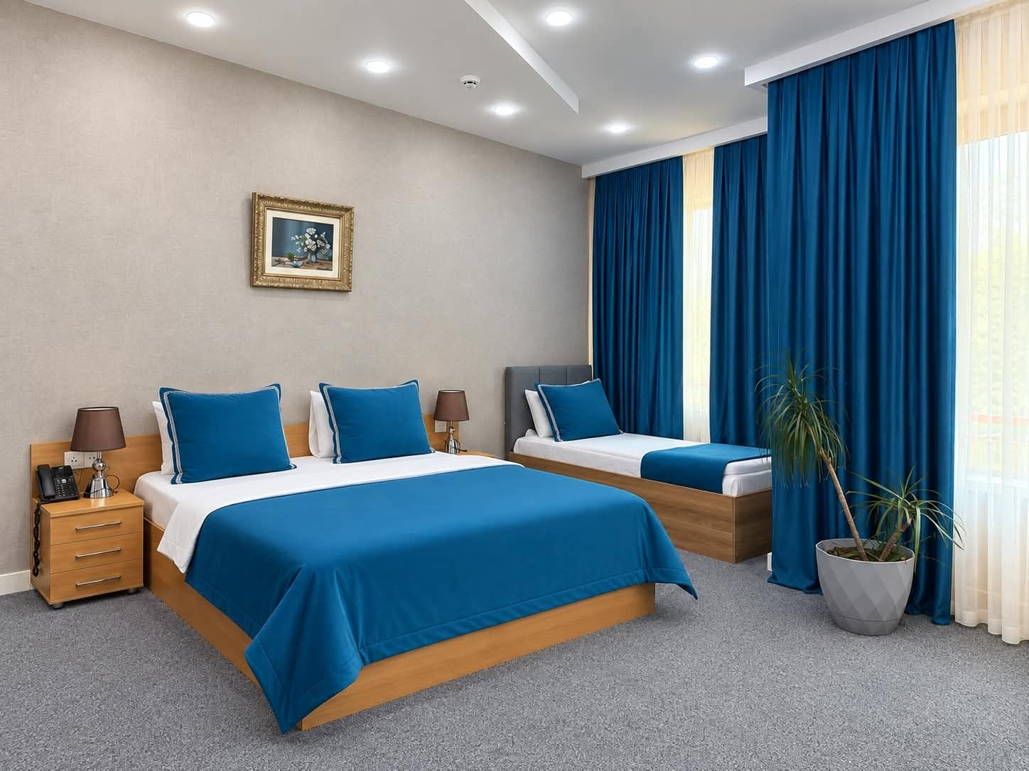 A hotel room with two beds, a nightstand, a lamp, a framed picture on the wall, and a potted plant.