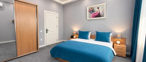 Un dormitorio moderno con una cama grande, mesitas de noche, un armario y una lámpara en el techo.