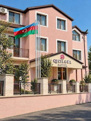 Un edificio de hotel con un balcón, una bandera y un letrero que dice 'Qizilqul Hotel'.