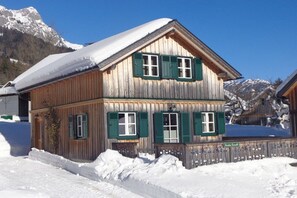 A wooden chalet with a sloped roof, green shutters, and a snow-covered landscape. - Gaiswinkler holiday home (Grundlsee)