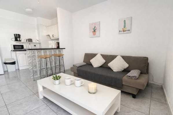 A modern living room with a sofa, a coffee table, and a kitchen in the background. - Apartment Chipeque (Arona)