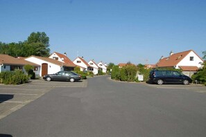 Eine Wohnstraße mit Häusern, parkenden Autos und blauem Himmel.
