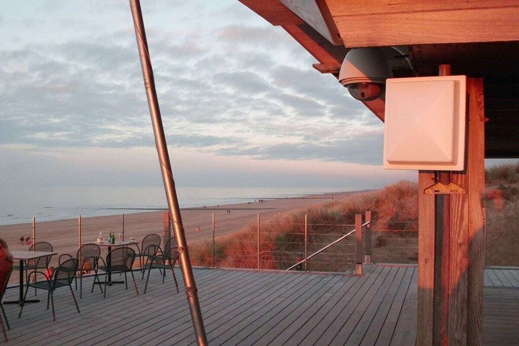 Eine Holzterrasse mit Sitzgelegenheiten mit Blick auf einen Strand.