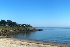 Eine Küstenlandschaft mit felsiger Küste, ruhigem Wasser und blauem Himmel.