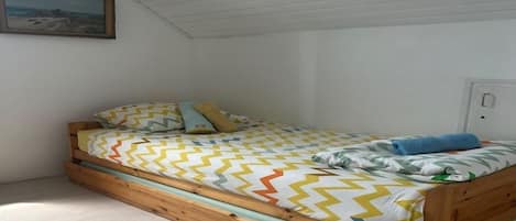 Ein Einzelbett mit Holzrahmen, einer gemusterten Bettdecke und Kissen.